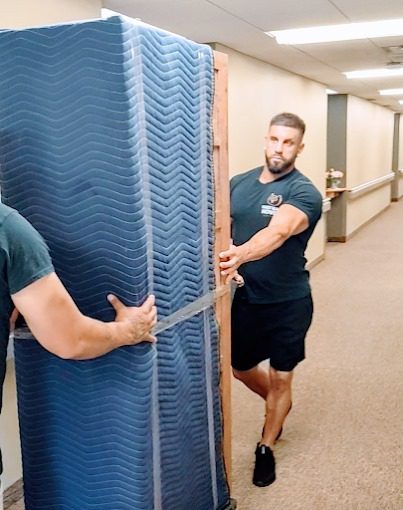 Person carrying a large mattress.